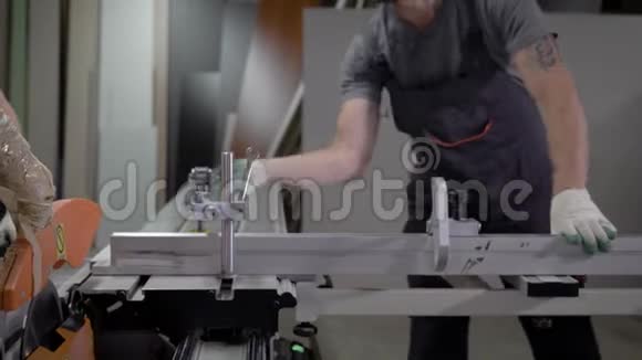 两名工业工人推木板通过切割机的近距离射击视频的预览图