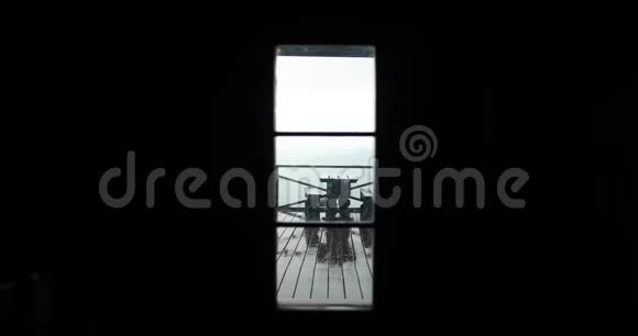 从外面看一个黑暗的房子雨落在桌子和门廊外面的长凳上视频的预览图