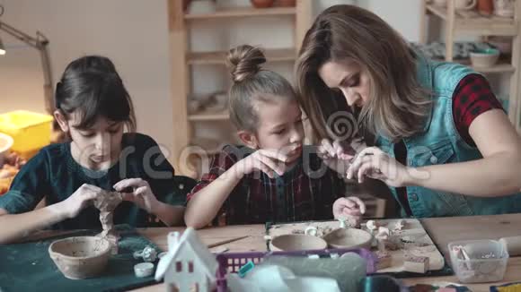 母亲和女儿热情地用陶器中的粘土塑造视频的预览图