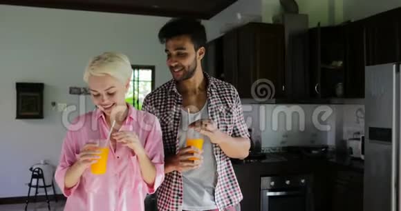 现代公寓中的情侣饮橙汁舞蹈年轻快乐男人与女人晨间交流视频的预览图