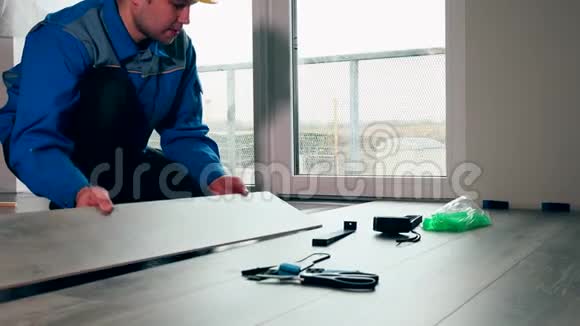 穿蓝色工作服的工人在白色房间铺木地板视频的预览图