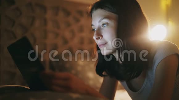 夜间躺在床上的年轻美女使用平板电脑的特写镜头视频的预览图