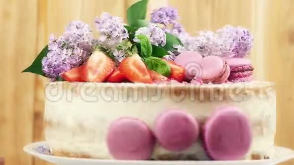 旋转婚礼蛋糕装饰紫色马卡龙切片草莓和丁香花4K内部拍摄视频的预览图