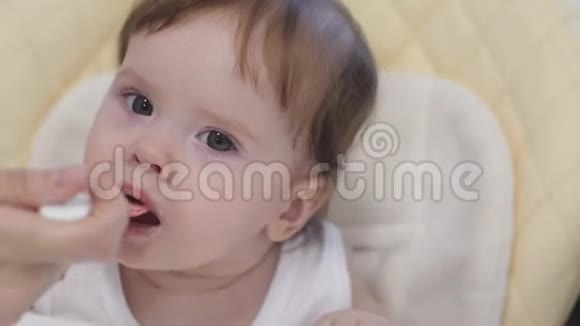 宝宝坐在厨房的高椅上吃汤匙口水和微笑的粥视频的预览图