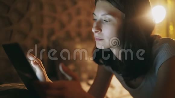年轻女性使用平板电脑是由于网络成瘾和失眠深夜躺在家里的床上视频的预览图