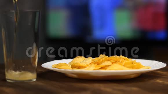 啤酒倒进杯子里薯片在桌子上足球在电视上视频的预览图