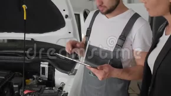 汽车师傅在平板电脑上显示技术状况汽车修理工在故障车辆上显示汽车修理工建议视频的预览图