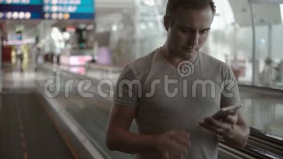严肃的帅哥在机场候机楼里用拖车在智能手机上和朋友聊天视频的预览图