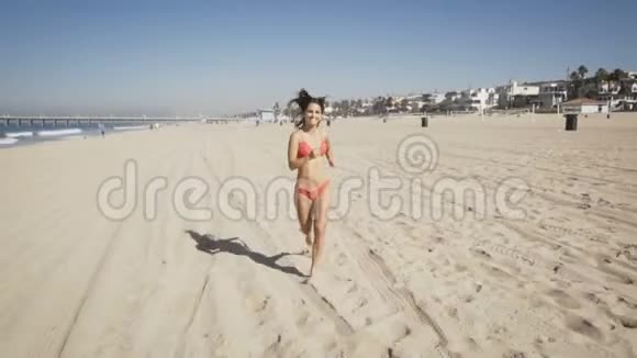 快乐的年轻女子在加州曼哈顿海滩跑步夏季视频的预览图