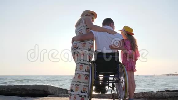 残疾男子与家人休息孕妇无效子女相互拥抱配偶在轮椅上拥抱妻子视频的预览图