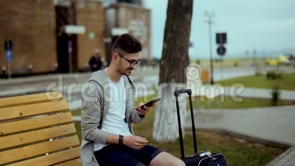机场上的年轻旅行者手里拿着智能手机微笑着视频的预览图