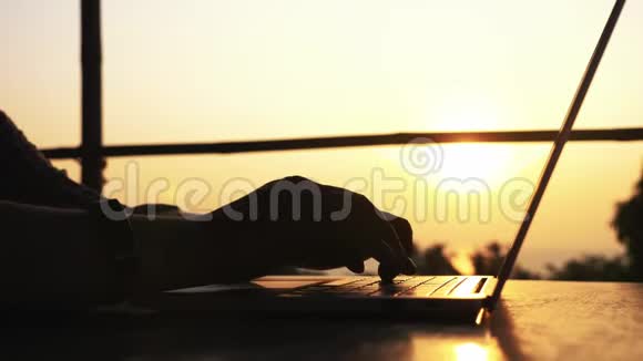 在美丽的夕阳下男性手在笔记本电脑上打字特写视频的预览图