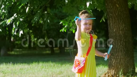 一个穿着黄色连衣裙的小女孩在中部玩肥皂泡户外玩得开心视频的预览图