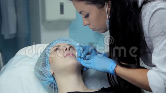 在美容院医生美容师把肉毒杆菌注射到女孩嘴唇上隆唇过程视频的预览图