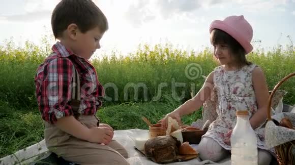 婴儿手里面包女孩在背光下待男孩的一块牛奶面包孩子们的鬼脸慢动作视频的预览图