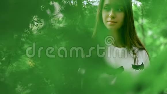 绿色森林中的时髦女孩在树叶后面摆姿势视频的预览图