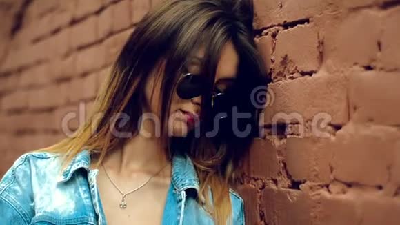 可爱的金发女郎戴着墨镜红唇跨过砖墙视频的预览图