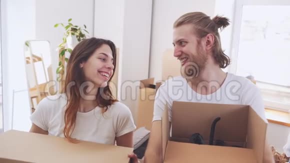 美丽快乐的白种人双手拿着盒子在他们的新公寓里装着东西幸福和感动的概念视频的预览图