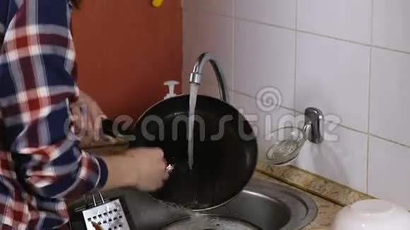 穿格子衬衫的女人洗锅把它放在桌子上快关门视频的预览图