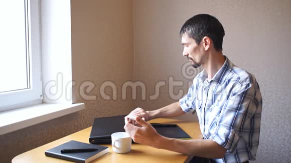 男人打开坐在桌子旁的笔记本电脑视频的预览图