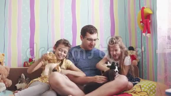 这位年轻的父亲和两个小女儿玩着柔软的玩具微笑着笑父亲喜欢和孩子在一起视频的预览图