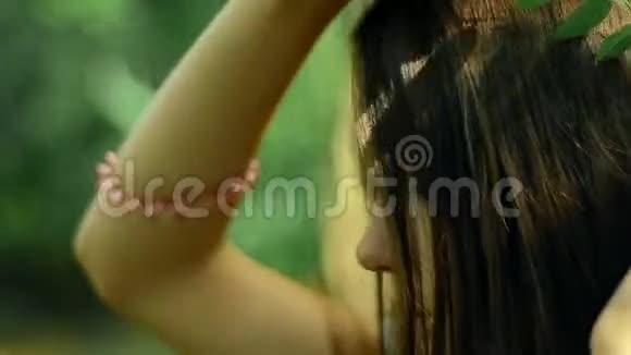 年轻的黑发在森林里的头发中插入叶子视频的预览图