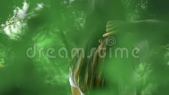 女孩在绿林中抚摸她的头发视频的预览图