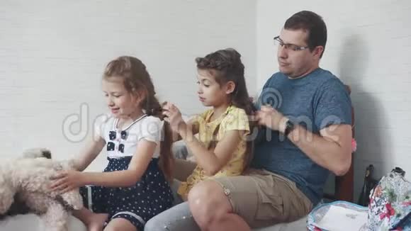 爸爸和两个小女儿在家父亲花时间和孩子在一起父亲给女儿做辫子视频的预览图