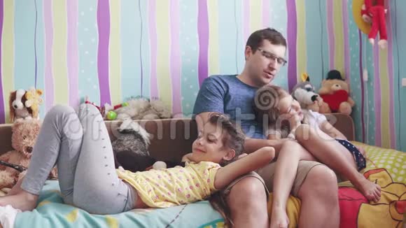 这位年轻的父亲和两个小女儿玩着柔软的玩具微笑着笑父亲喜欢和孩子在一起视频的预览图