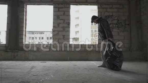 无家可归的人几乎不在废弃的大楼里拖一个垃圾袋视频的预览图