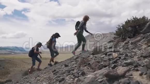 母亲和两个孩子去山里远足一群旅行者上山家庭旅行者视频的预览图