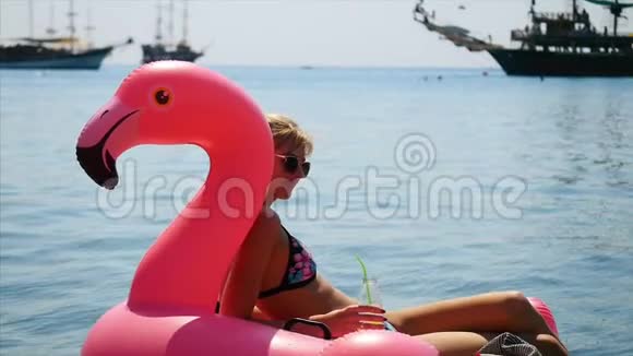 美丽的年轻女子在土耳其Faselis海滩的红色充气天鹅上放松视频的预览图