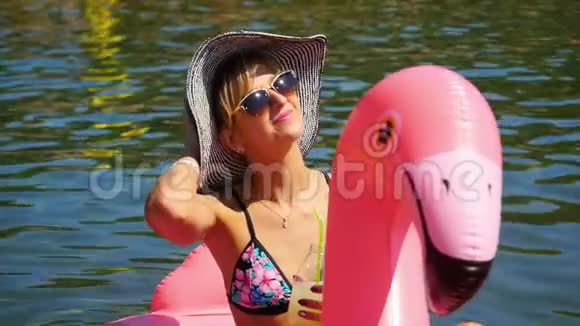 美丽的年轻女子在阳光下放松在土耳其法塞利斯海滩上的红色充气天鹅上视频的预览图