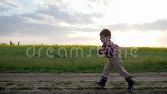 小男孩沿着田间路奔跑奔跑的孩子快乐的孩子在城外玩耍健康的童年干净的环境视频的预览图