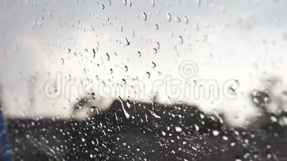 在恶劣天气时用模糊背景关闭车窗上的雨滴水滴落在玻璃上视频的预览图