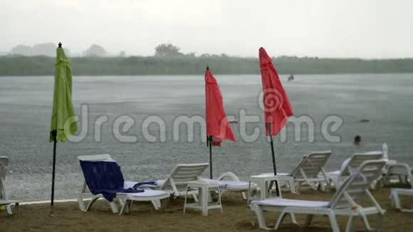 夏雨雷雨强降雨在空旷的沙滩上河边孤独的空的空的阳光的沙滩伞的视频的预览图