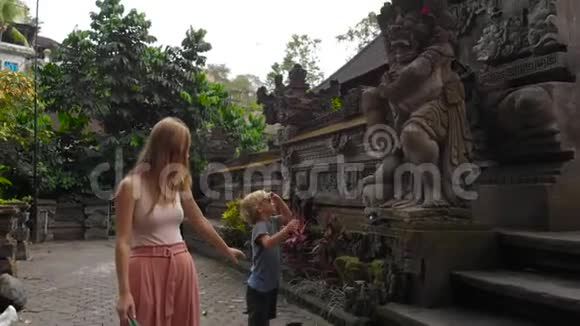 在Ubud的PuraGunungLebah寺庙周围行走的年轻女子和赫尔小子的缓慢动作稳定射击视频的预览图