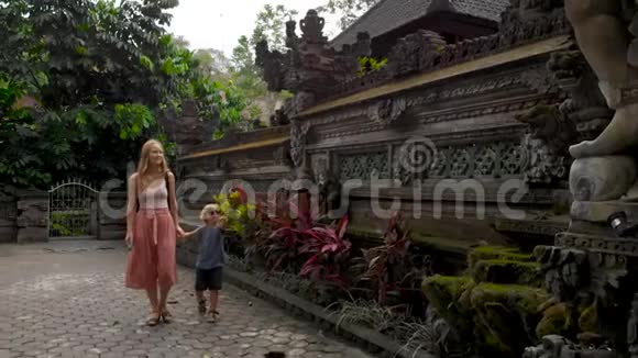 在Ubud的PuraGunungLebah寺庙周围行走的年轻女子和赫尔小子的缓慢动作稳定射击视频的预览图