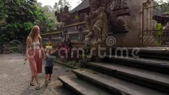 在Ubud的PuraGunungLebah寺庙周围行走的年轻女子和赫尔小子的缓慢动作稳定射击视频的预览图