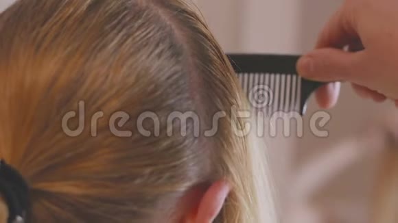 一位留着长发的金发女子正在镜子前梳头为染发根作准备视频的预览图