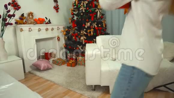 带着耳机听音乐的女孩把礼物放在圣诞树下视频的预览图