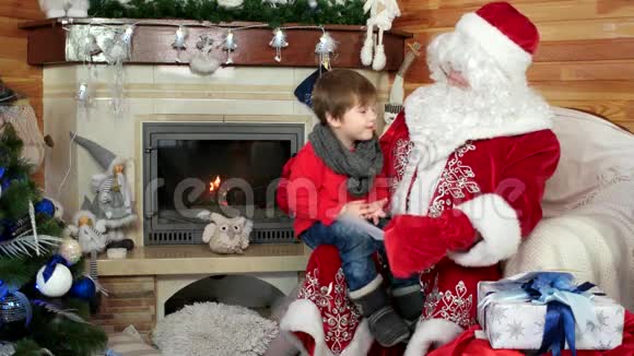 男孩坐在圣诞老人腿上孩子在信封里给圣尼古拉斯他的圣诞愿望单视频的预览图