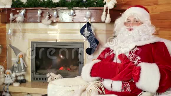 微笑的圣诞老人迎接游客热情好客的圣诞老人房间里有壁炉和装饰的圣诞树视频的预览图