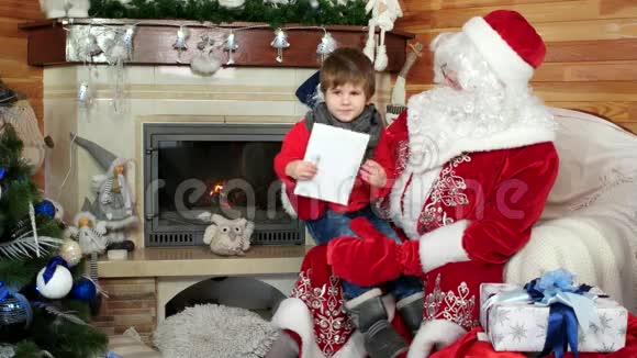 圣诞老人腿上的小男孩在诉说的圣诞祝福小男孩在圣尼古拉斯的冬居视频的预览图