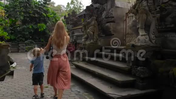 在Ubud的PuraGunungLebah寺庙周围行走的年轻女子和赫尔小子的缓慢动作稳定射击视频的预览图