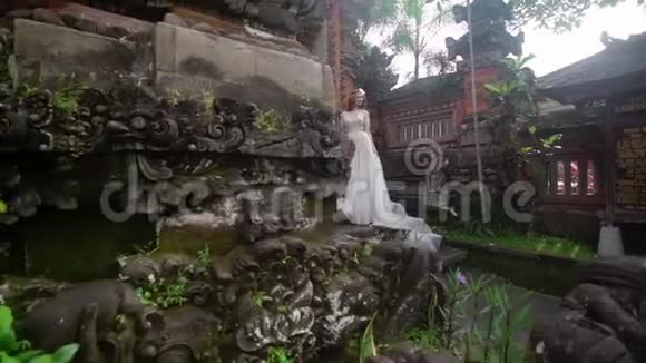 美丽的新娘在巴厘岛的佛寺附近摆姿势在附近散步浪漫的婚礼视频的预览图