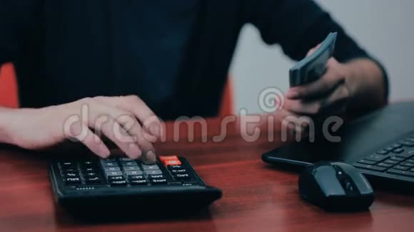 一个拿着计算器和钞票数钱的人财务商业经济视频的预览图
