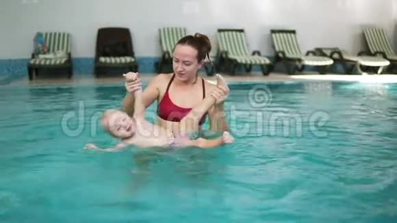 快乐微笑的小孩子正和妈妈一起在游泳池里游泳年轻的妈妈在旋转视频的预览图
