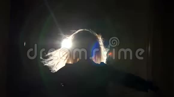 一个在黑暗中轻飘飘的头发的华丽女孩的剪影视频的预览图