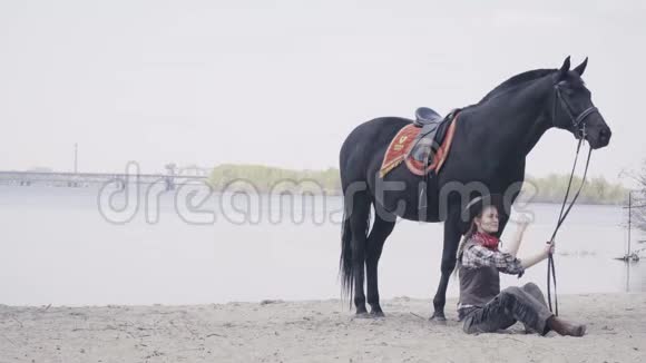 女人和她的黑马坐在沙滩上4K视频的预览图